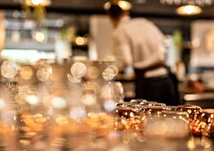 Serveur en tablier derrière le bar du Monkey Place à La Roche-sur-Yon, verres et timbales cuivrées sous les lumières dorées du réveillon